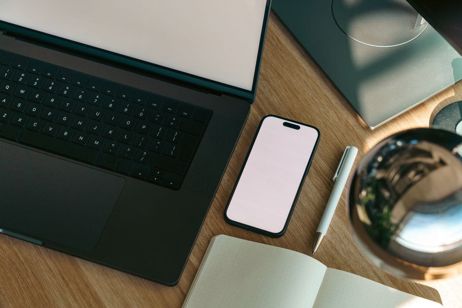 A modern desk photographed from above with a laptop and a smartphone, both screens blank