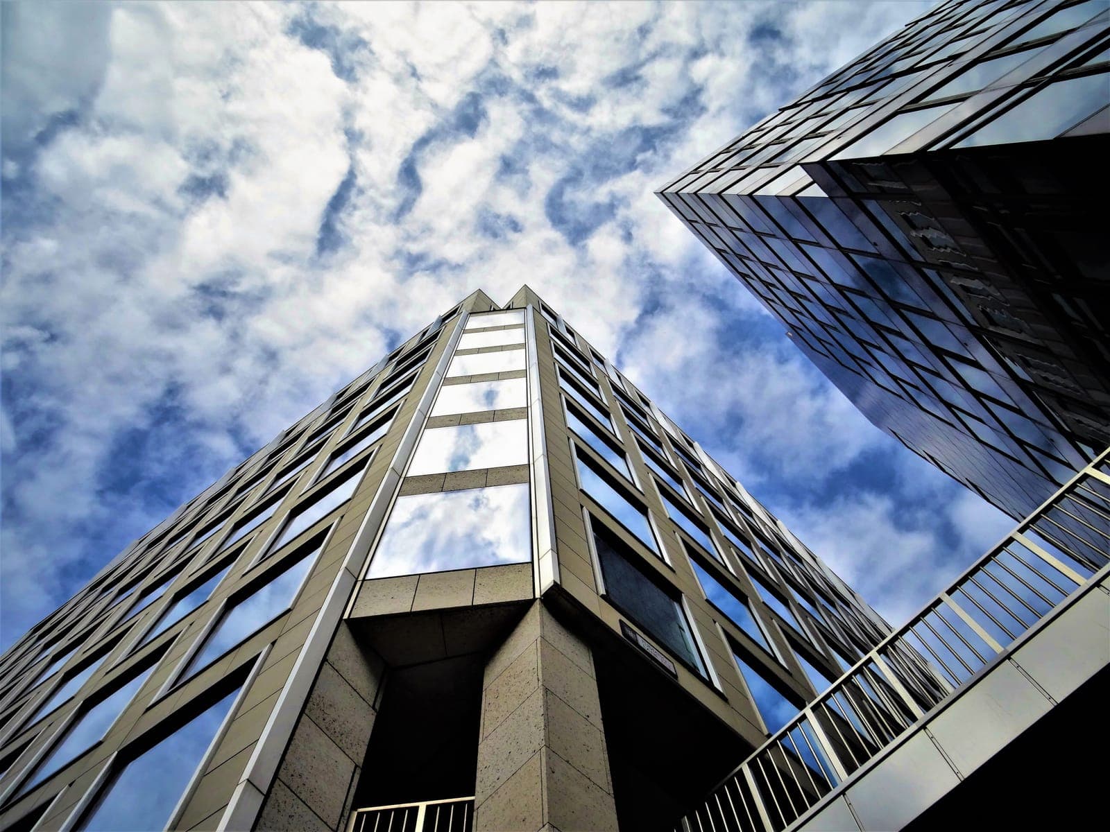 Low-angle view of a modern glass office building against a blue sky