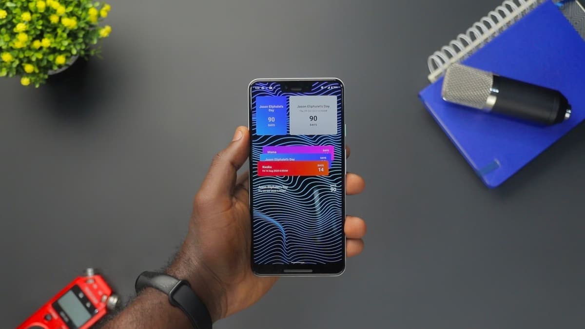 A hand holding a smartphone showing a stack of app notifications