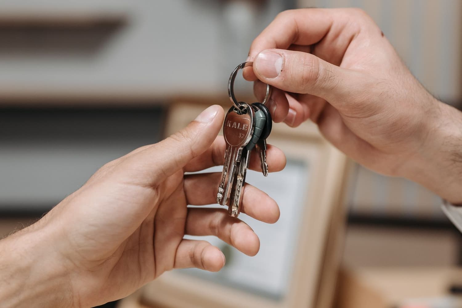 Two hands exchanging a set of keys indoors