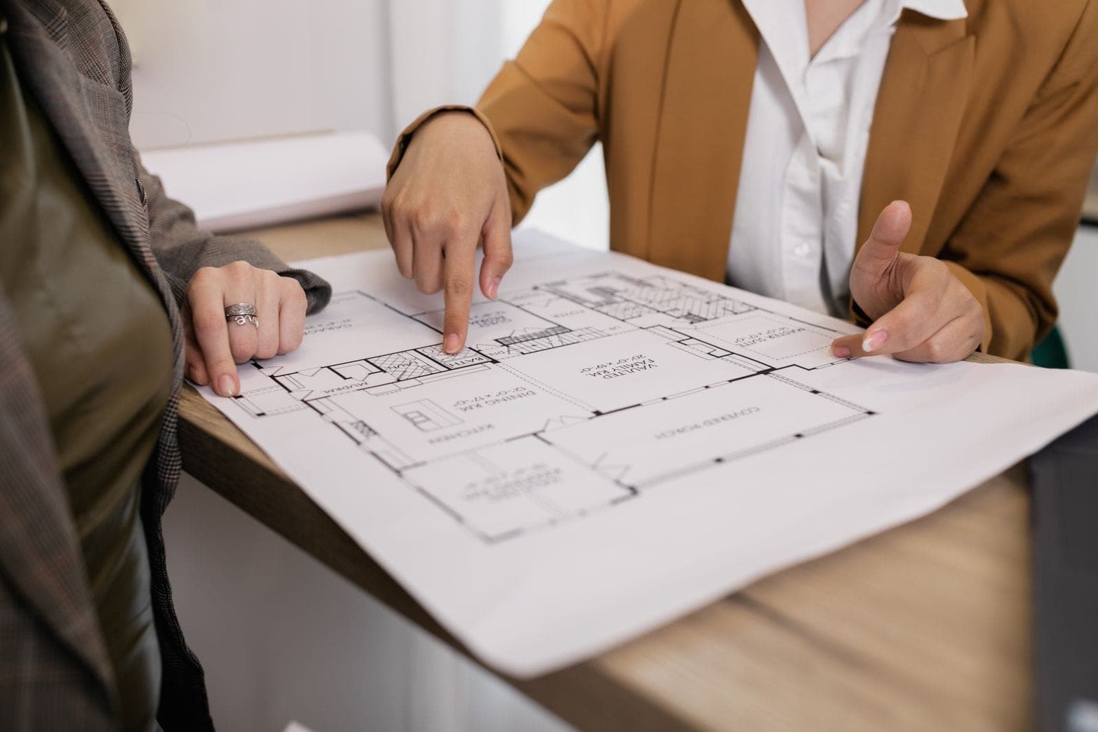 Two professionals reviewing an architectural floor plan together at a desk