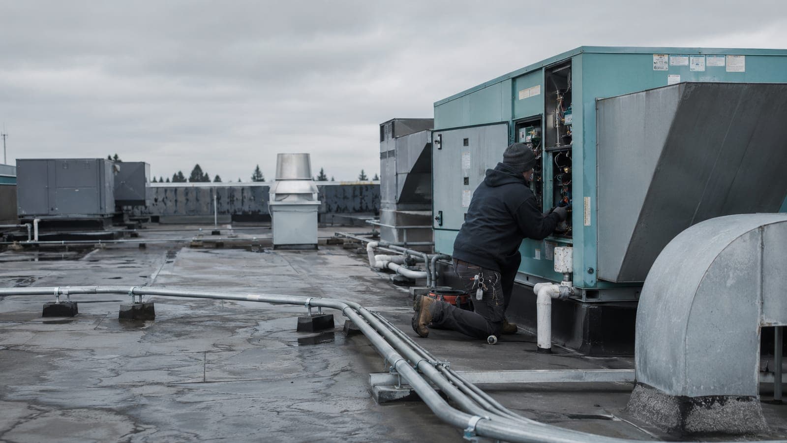 A technician servicing rooftop HVAC units on a commercial building